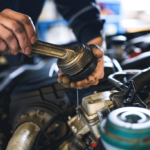 A mechanic showing how to chain oil in a car engine.