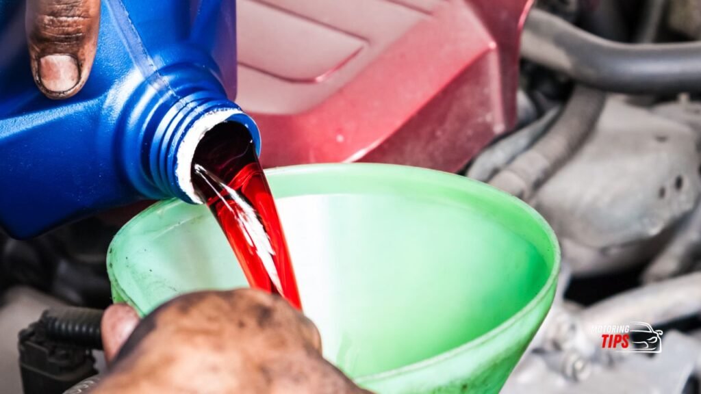 Mechanic pouring a Red Color Transmission Fluid into a car engine