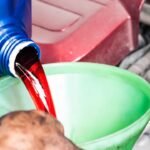 Mechanic pouring a Red Color Transmission Fluid into a car engine