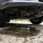 Water dripping from under a parked car onto a driveway