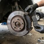Mechanic holding a new brake pad next to a brake disc and caliper