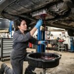 Mechanic draining red transmission fluid into a drain pan